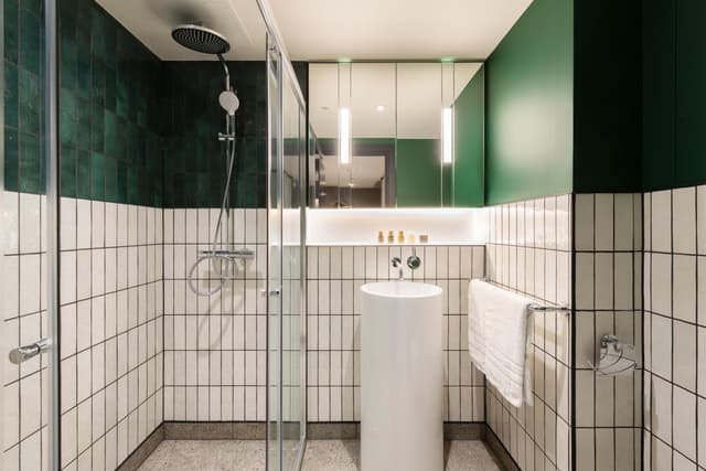 green and white tiled bathroom with a walk in shower