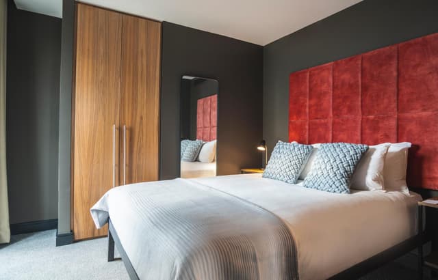 bedroom with a red headboard and white bedding