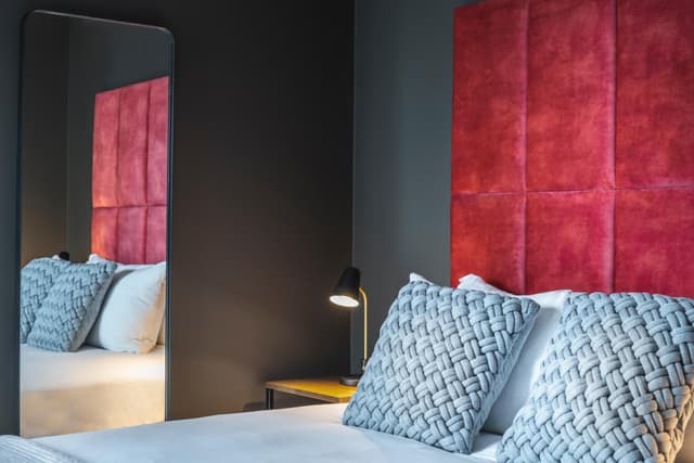photo of a bedroom with two beds and a red headboard