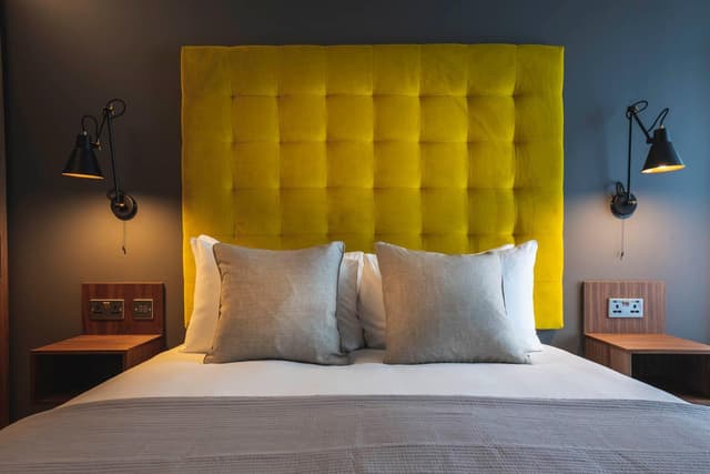 yellow upholstered headboard above a white bed