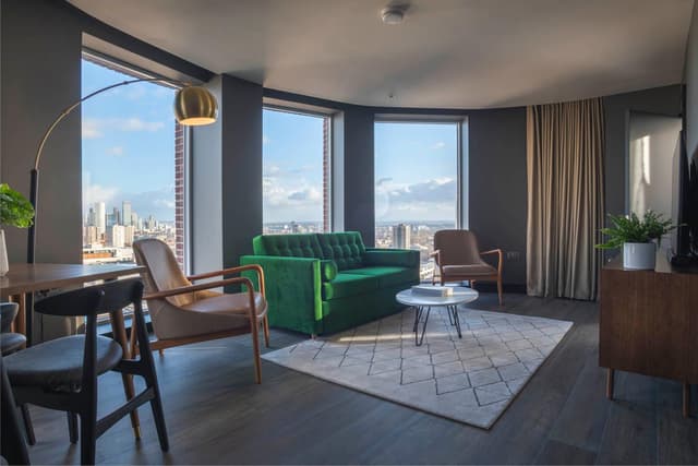 photo of a living room with a green couch and chairs