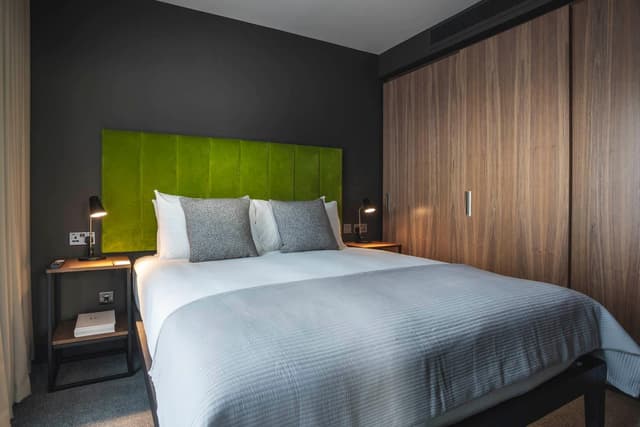 bedroom with a green headboard and wooden closets