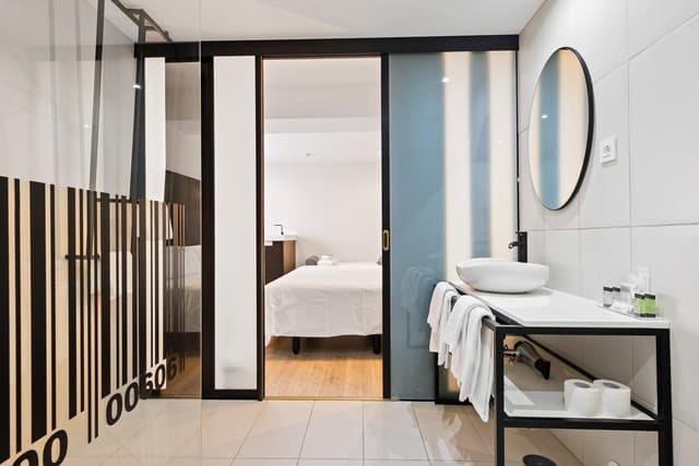 Modern bathroom with a white vessel sink, black metal frame, and glass partition.