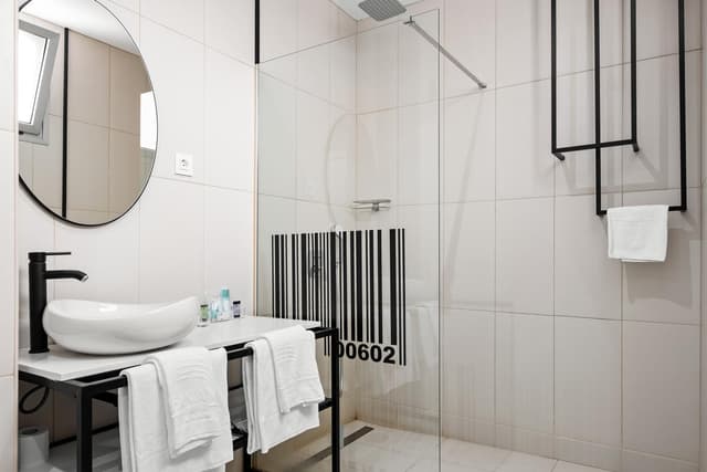Bathroom with a white vessel sink, black faucet, and a glass-enclosed walk-in shower.