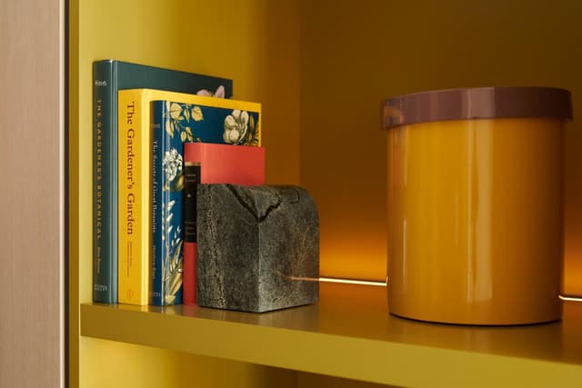yellow book shelf with books and a candle on it