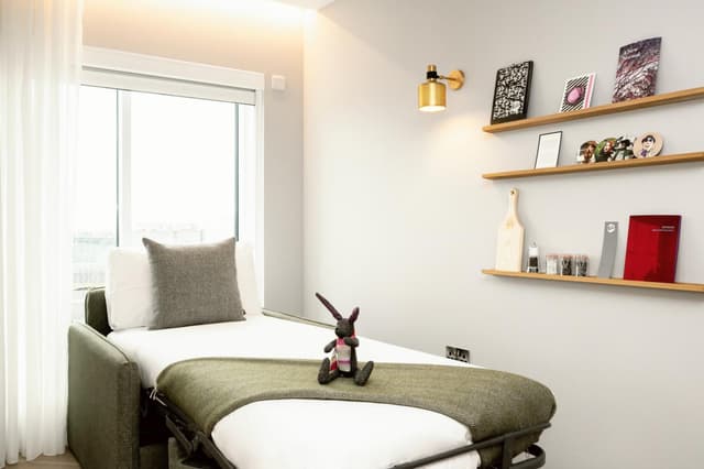 single bed in a small room with a view of the city
