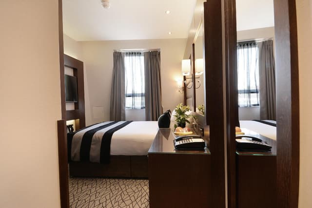hotel room with a bed, desk, and television