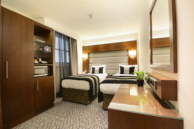 hotel room with two beds and a desk in front of it