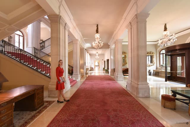 woman in a red dress walking down a long hallway
