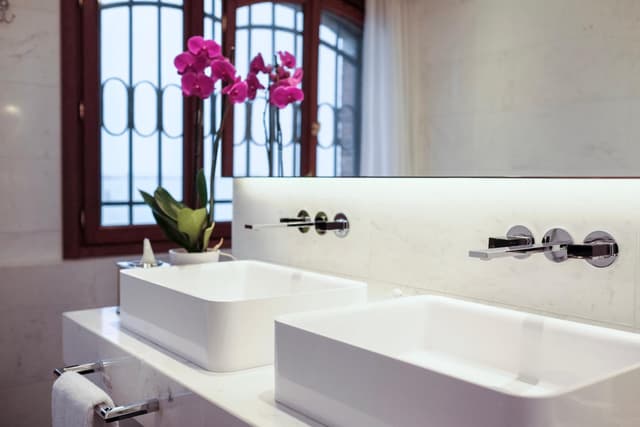 bathroom with two sinks and a vase of pink flowers