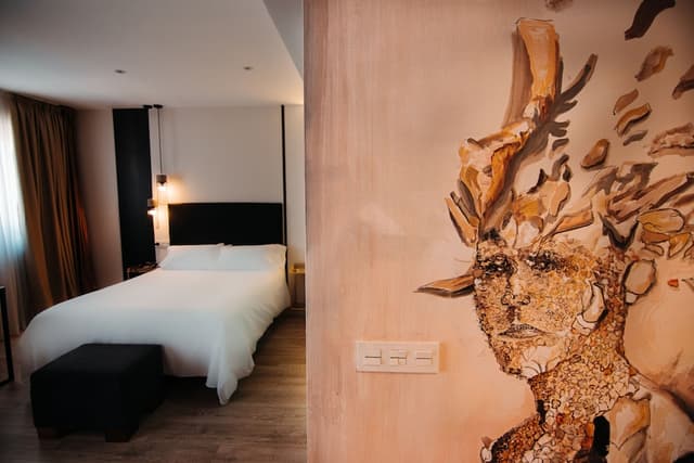 Hotel bedroom with a white bed, black headboard, and a large wall mural.